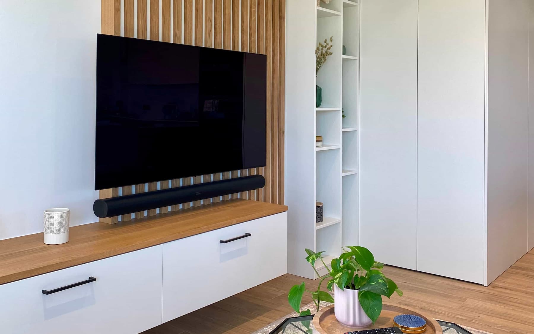 Meuble TV sur mesure blanc avec claustra bois dans un salon d'appartement