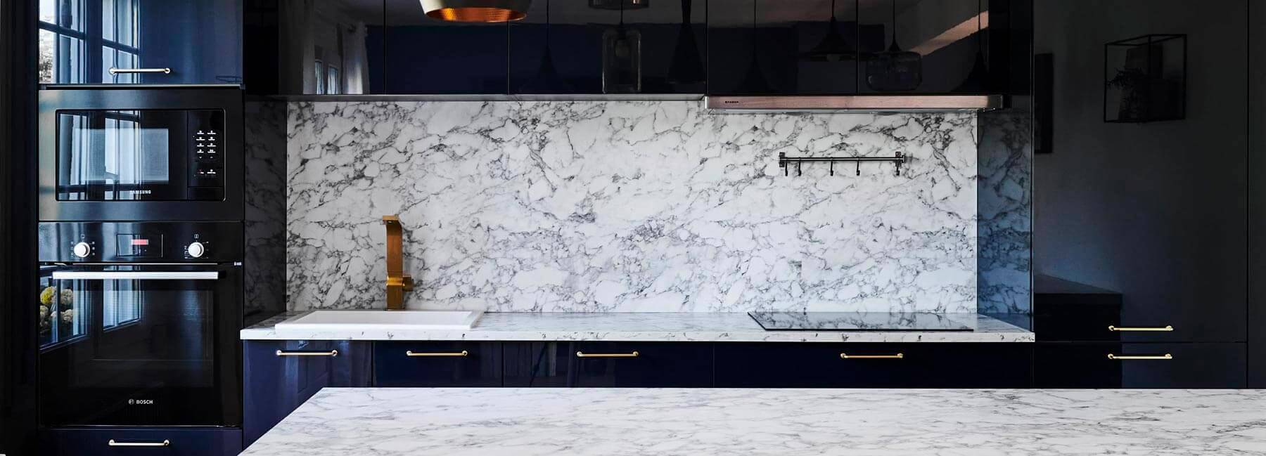 Gros plan sur la crédence effet marbre blanc d'une cuisine sur mesure à Paris