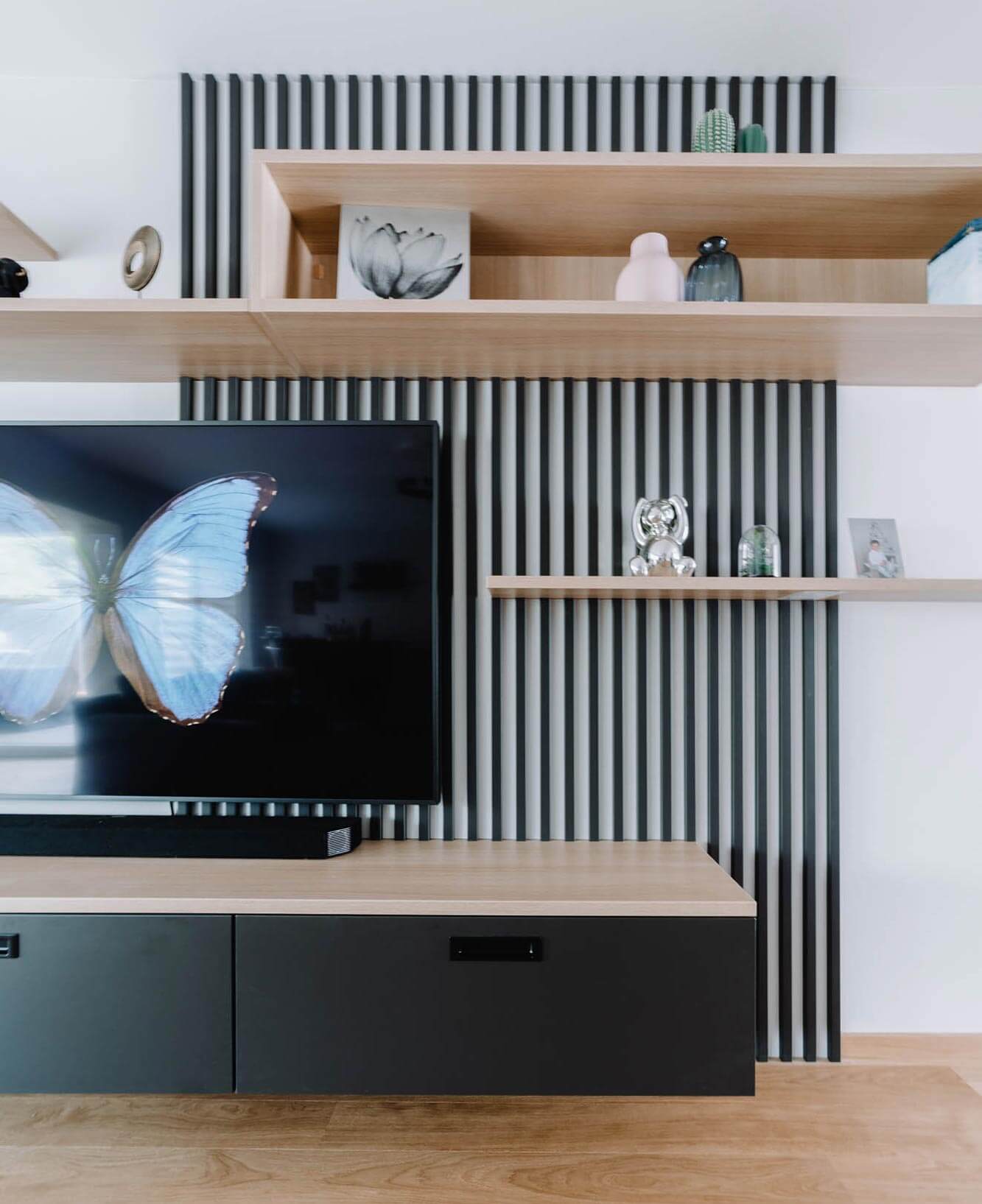 Meuble TV sur mesure claustra noir et panneaux en bois clair réalisé par BeHome Interiors Luxembourg