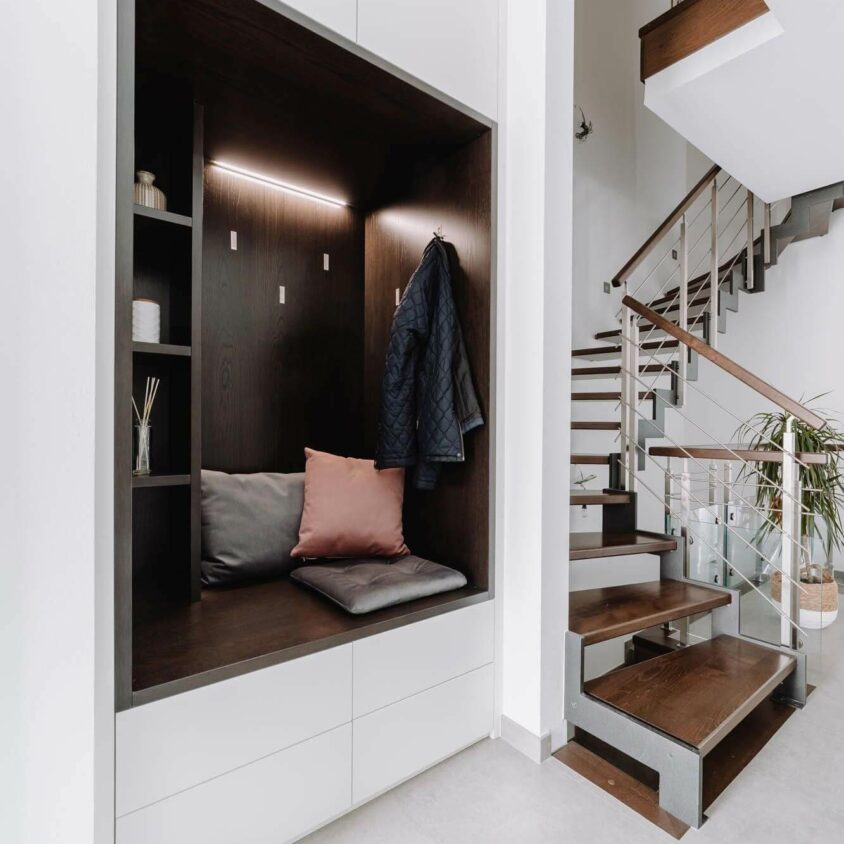 Aménagement d'une entrée à Paris avec un meuble placard blanc et niche bois sombre et éclairage