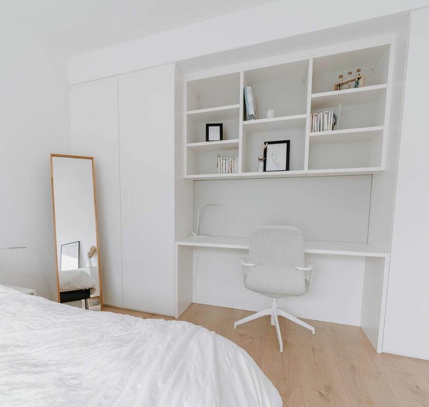 Aménagement d'une chambre blanche avec armoire portes battantes et bureau bibliothèque entre les armoires