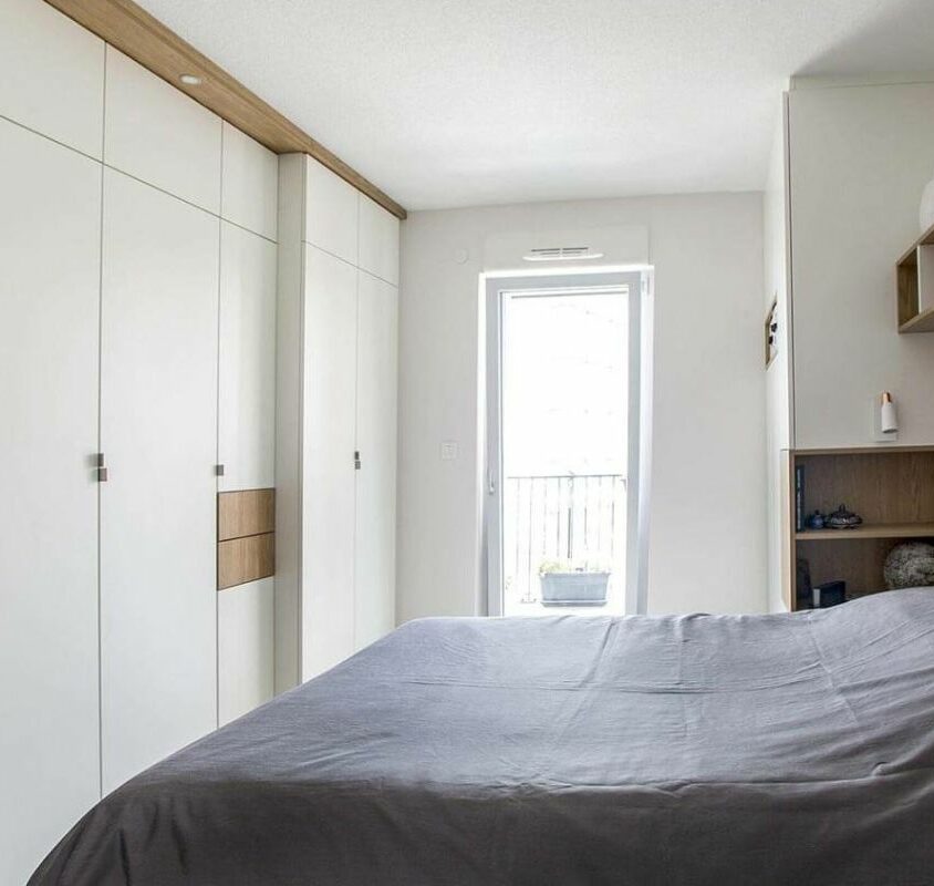 Aménagement d'une petite chambre avec armoire sur mesure blanche et bois clair le long d'un mur et tête de lit intégrée