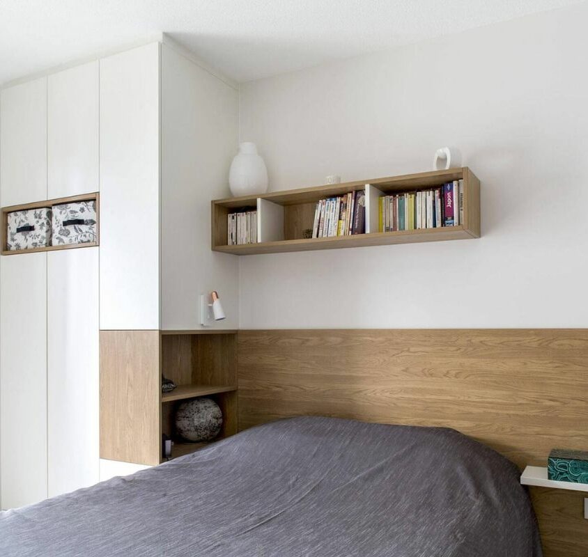 Armoire avec tête de lit intégrée couleur blanche et bois clair dans une petite chambre