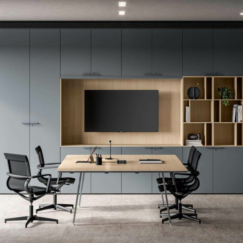 Salle de réunion avec table bois carré et grand mur de rangement pour archives et TV