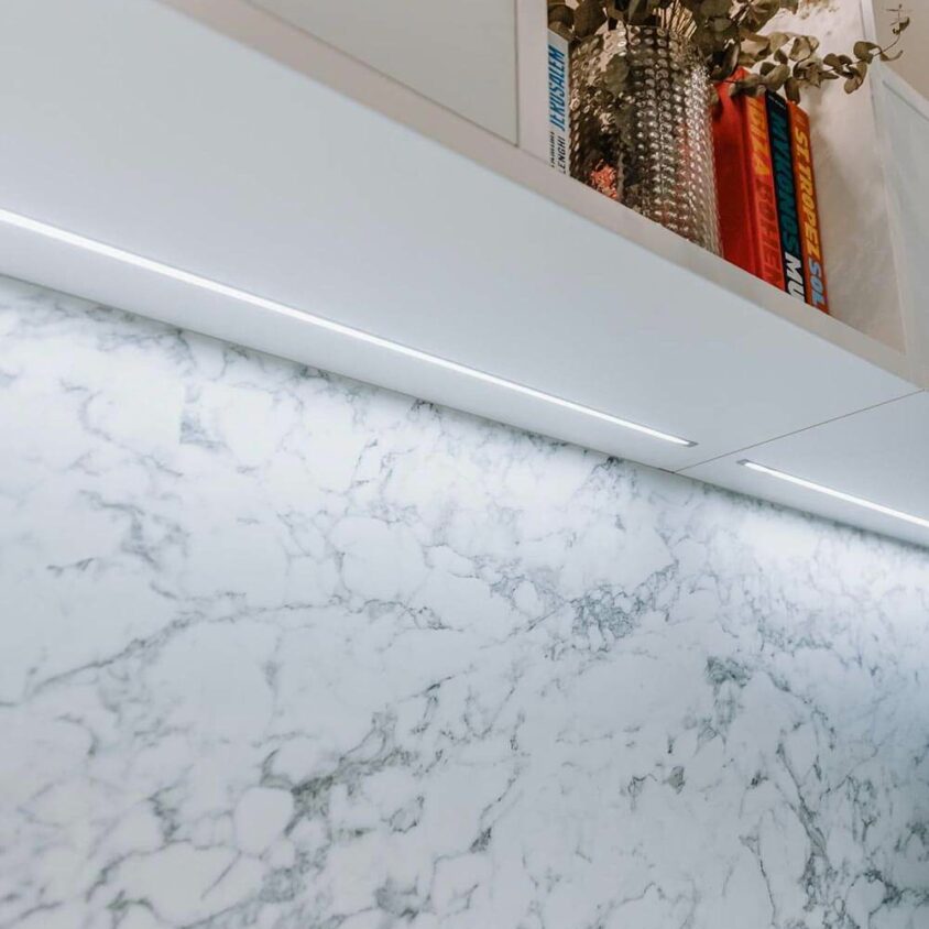 Bureau blanc sur mesure dans un appartement à Genève avec rangements et éclairage en surplomb