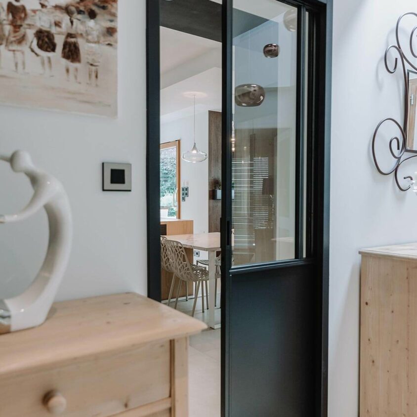 Aménagement d'intérieur global de maison à Bussigny près de Genève avec porte coulissante entre la cuisine et l'entrée