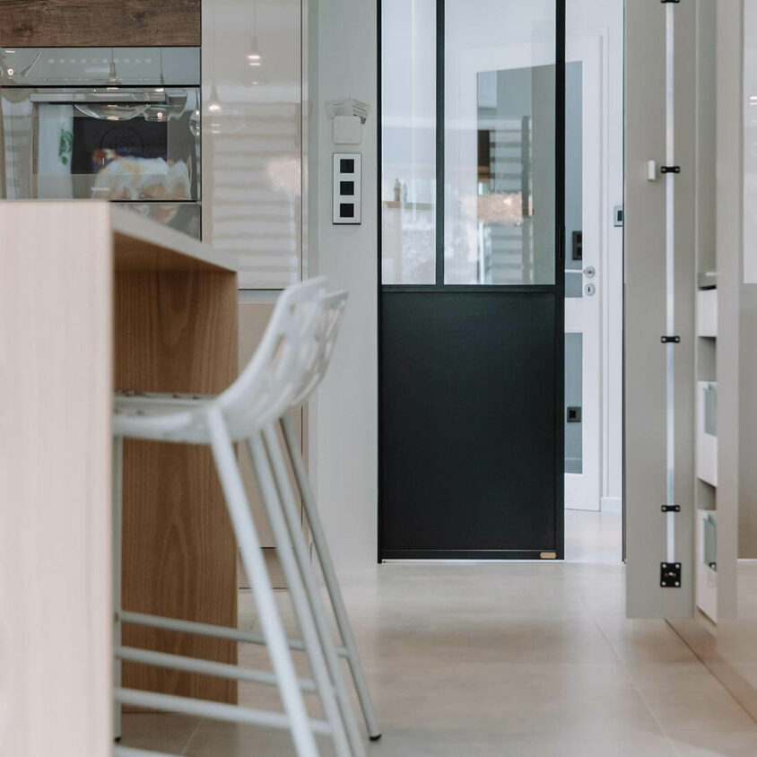 Aménagement d'intérieur global de maison à Bussigny près de Genève avec porte coulissante entre la cuisine et l'entrée