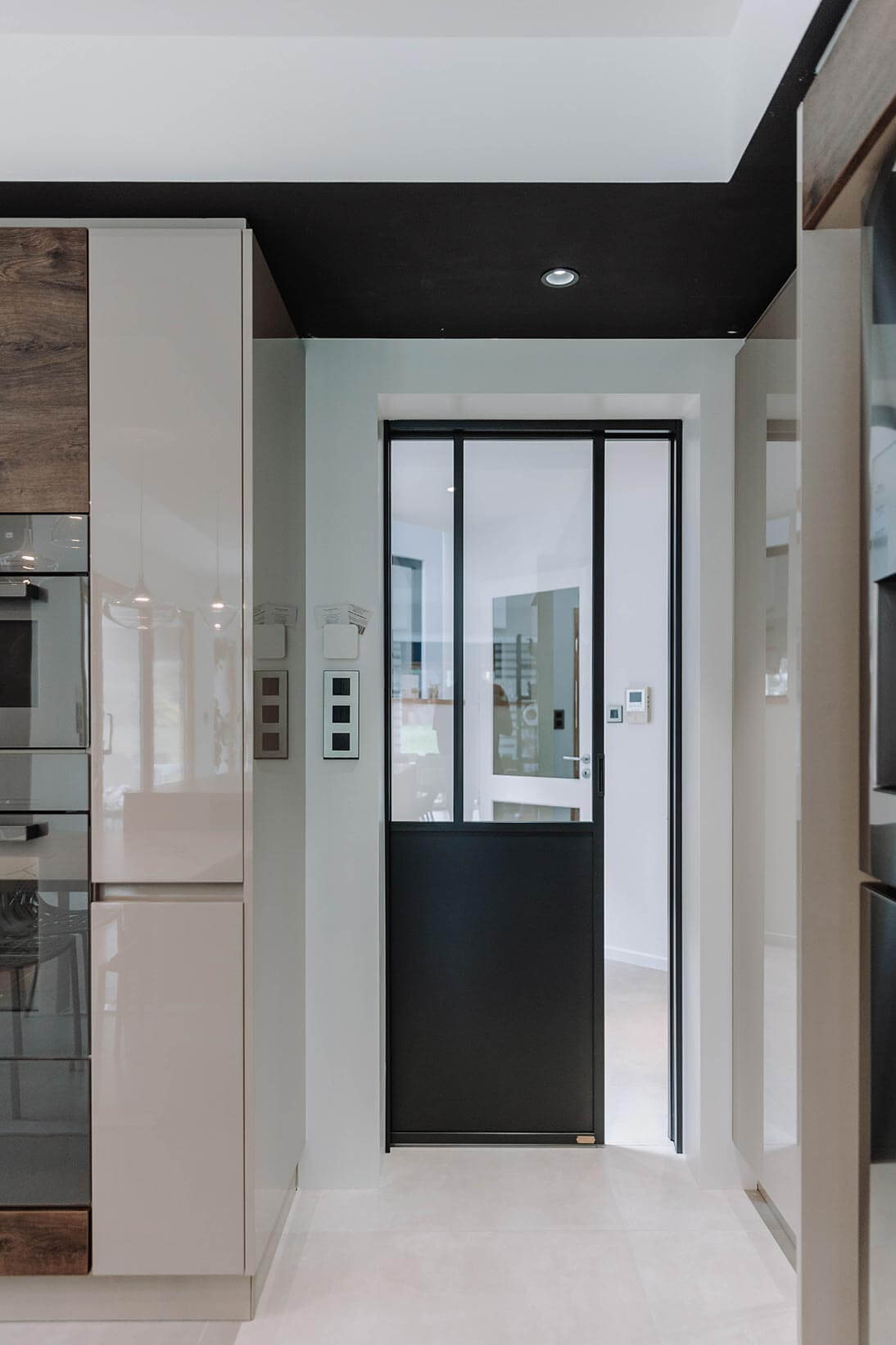 Aménagement d'intérieur global de maison à Bussigny près de Genève avec porte coulissante entre le hall d'entrée et la cuisine