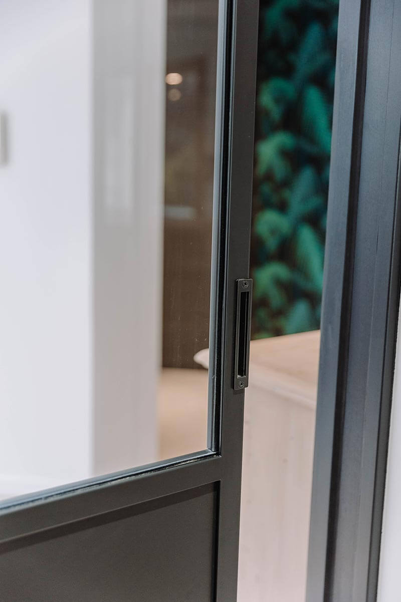 Aménagement d'intérieur global de maison à Bussigny près de Genève avec détail poignée de la porte coulissante entre la cuisine et l'entrée
