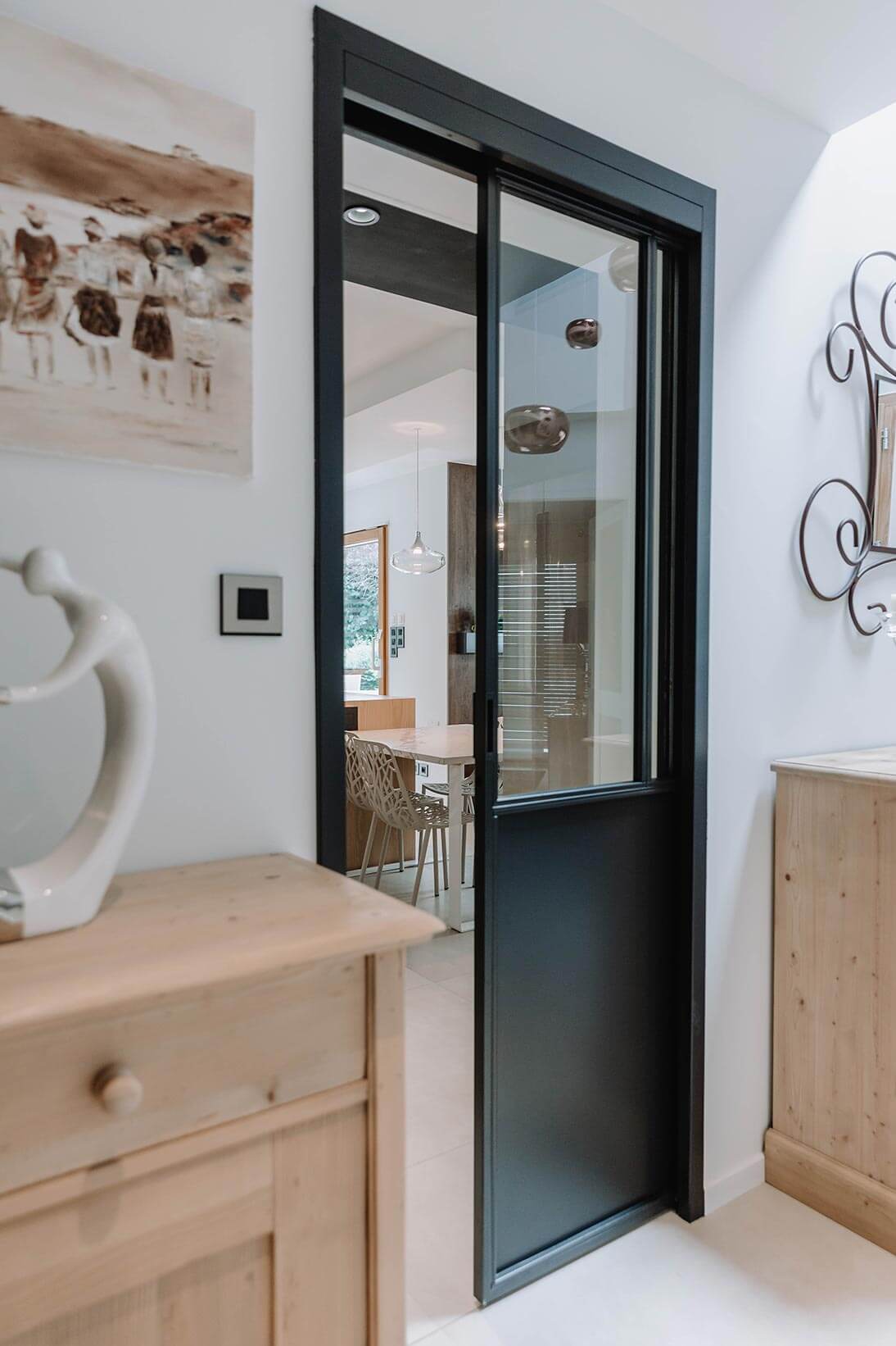 Aménagement d'intérieur global de maison à Bussigny près de Genève avec porte coulissante entre la cuisine et l'entrée