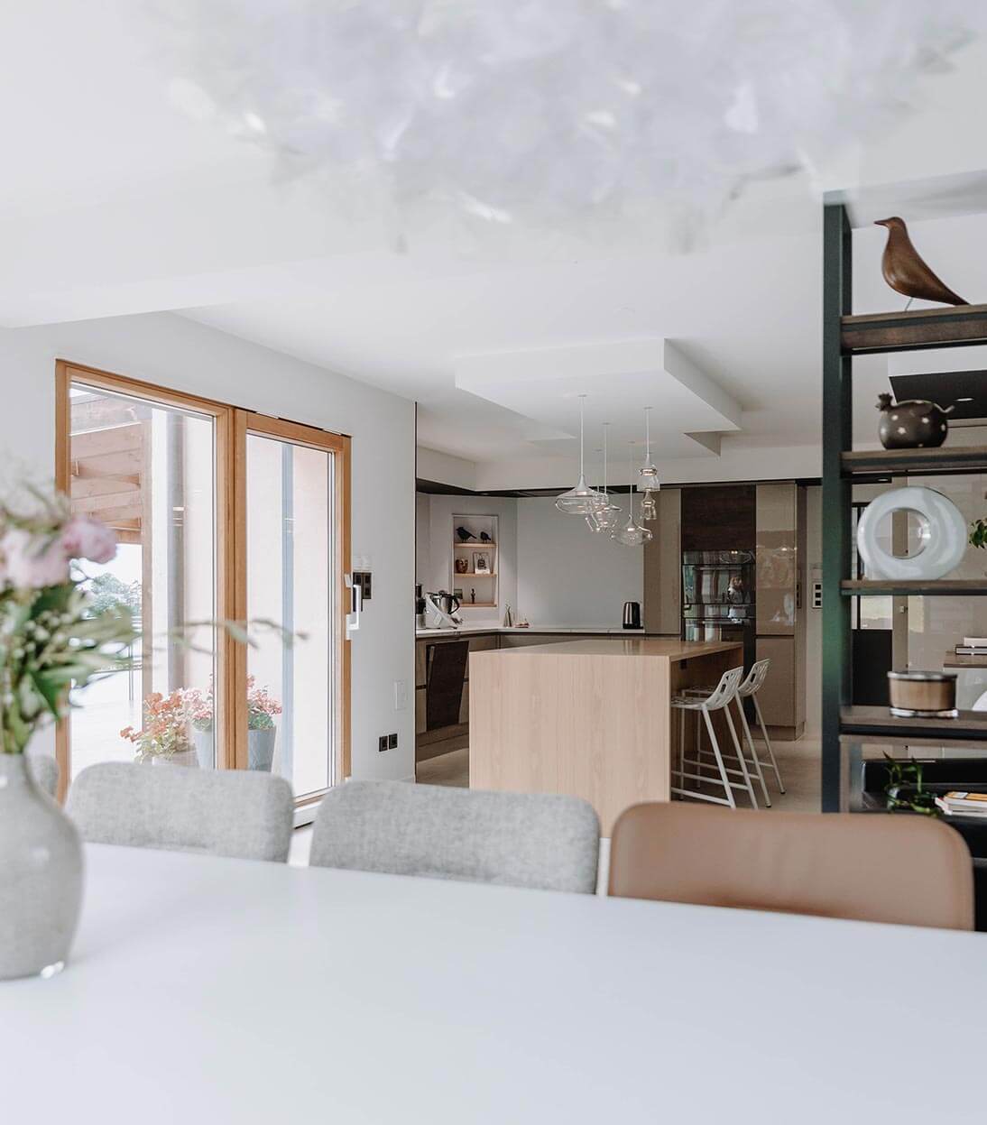 Aménagement d'intérieur global de maison à Bussigny près de Genève, vue sur étagère sur mesure et cuisine depuis le salon
