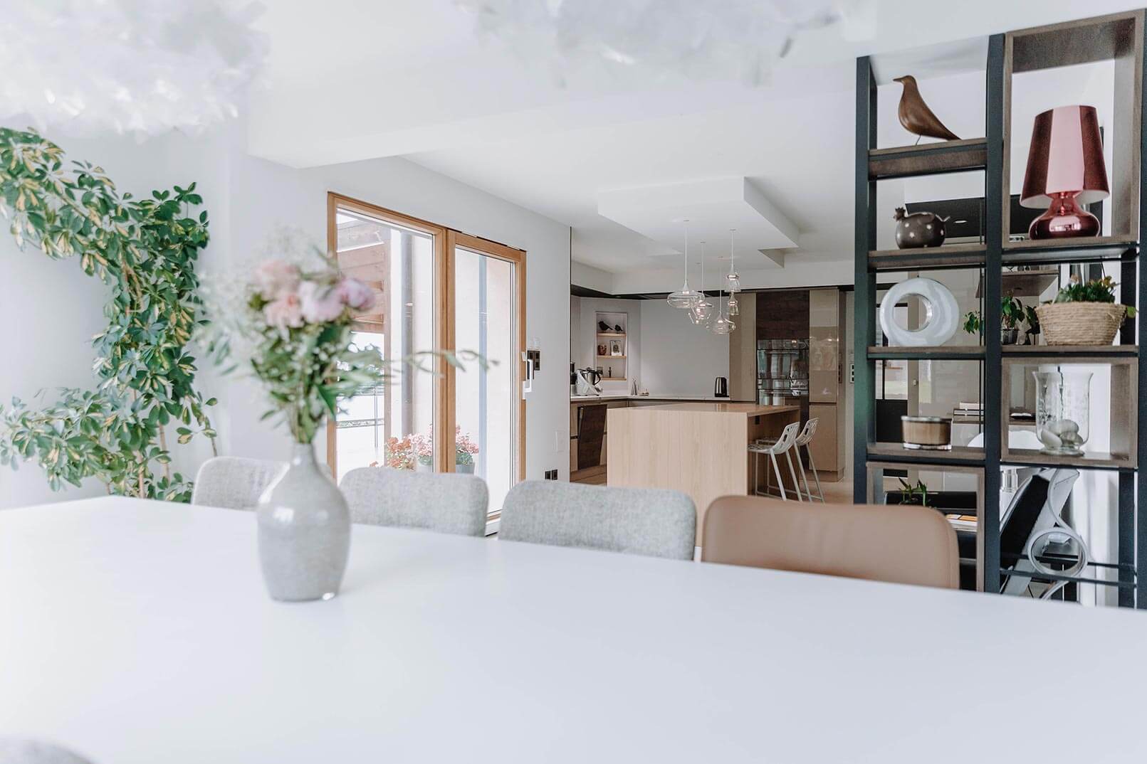 Aménagement d'intérieur global de maison à Bussigny près de Genève, vue sur étagère sur mesure et cuisine depuis le salon
