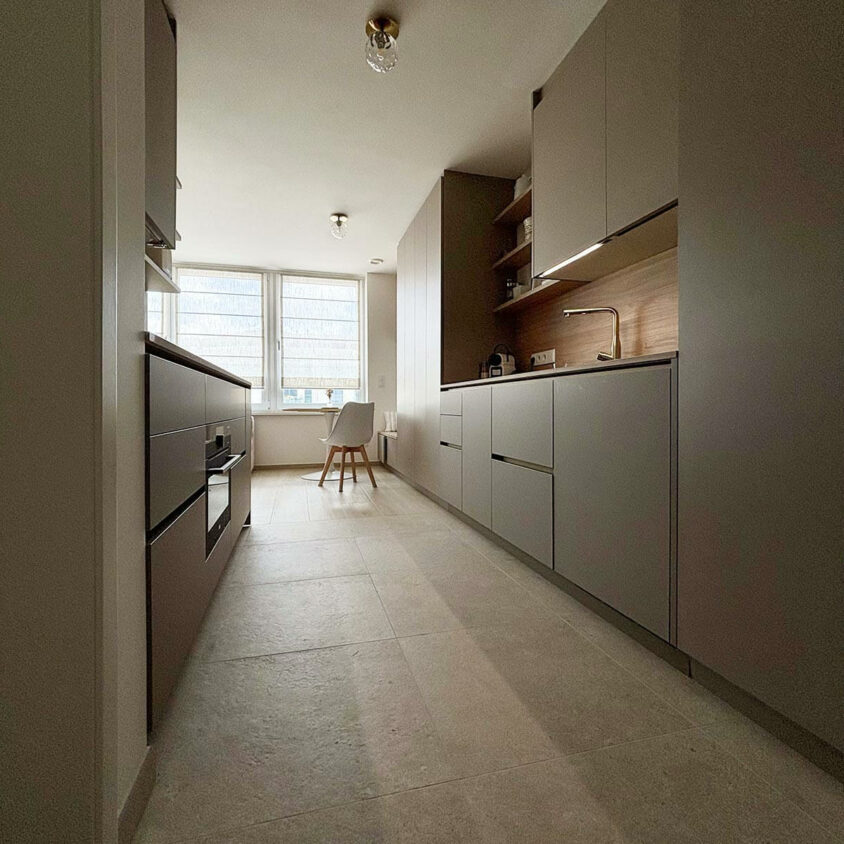 Aménagement intérieur d'un studio destiné à la location meublée avec longs meubles de rangements et cuisine