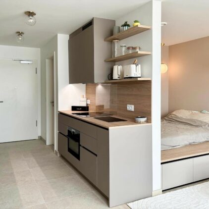 Aménagement intérieur d'un studio destiné à la location meublée avec longs meubles de rangements, cuisine et espace lit