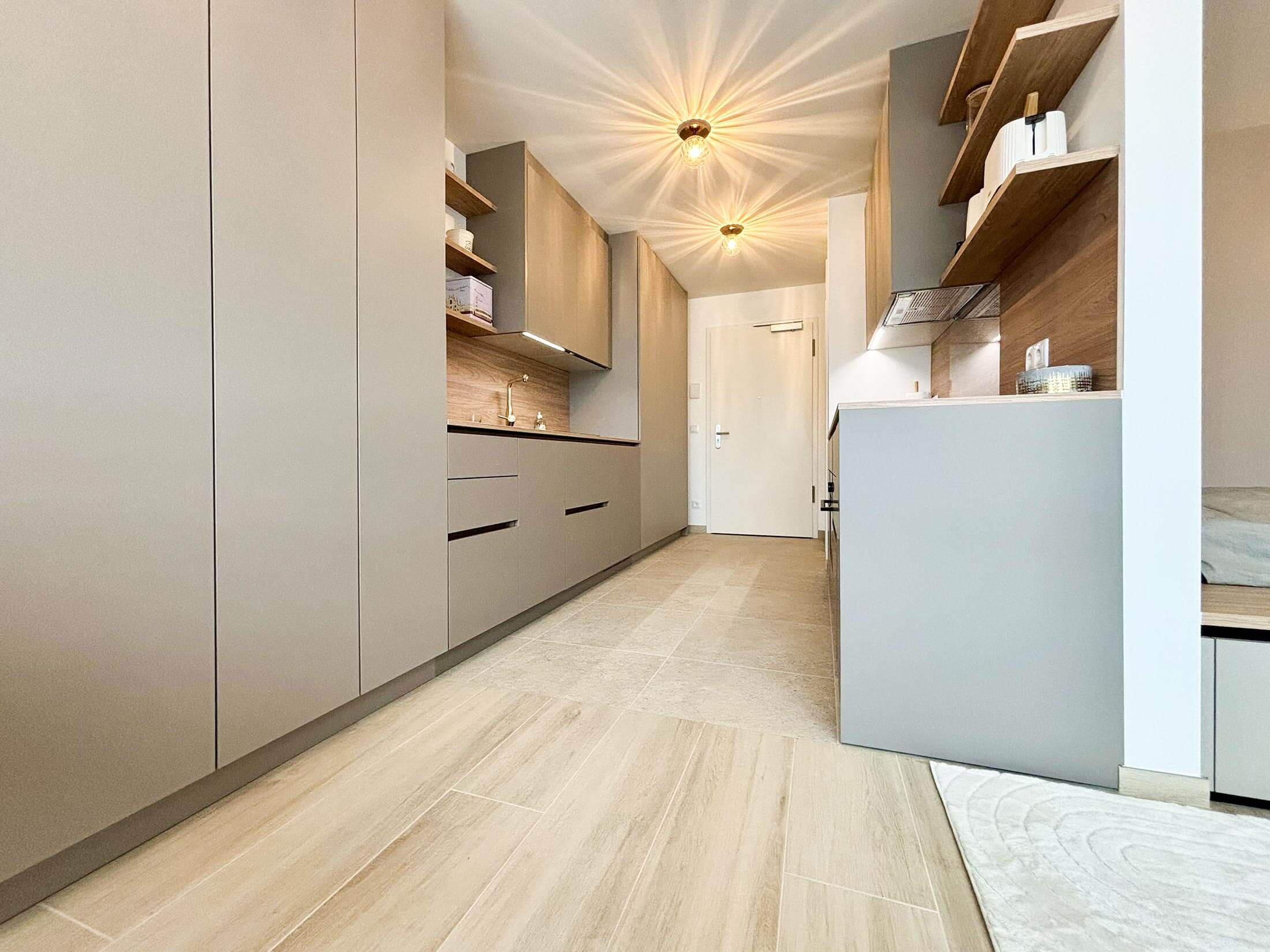 Aménagement intérieur d'un studio destiné à la location meublée avec longs meubles de rangements et cuisine